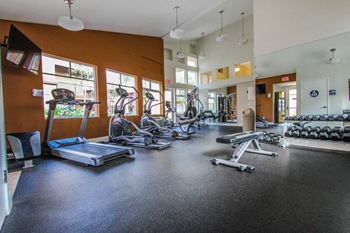 A gym with cardio equipment and weights on the floor