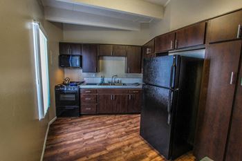 A kitchen with dark wood cabinets and a black refrigerator