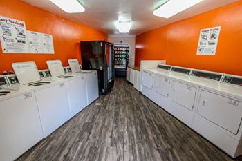 A washer and dryer room with a row of washes and dryers