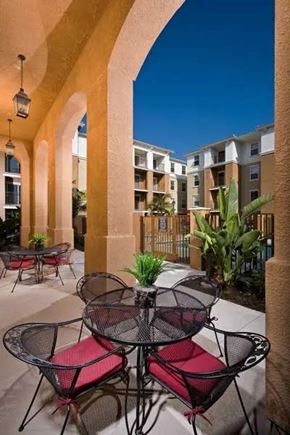 Buena Park apartment for rent - A patio with a table and chairs is surrounded by arches.