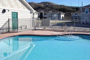Globe apartment for rent - a pool with a fence around it and houses in the background