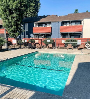 Selma apartment for rent - A swimming pool in front of a building with red and grey balconies.