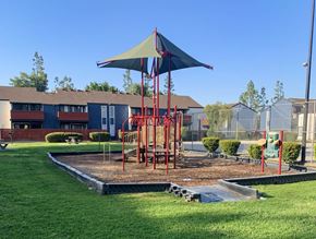 Selma apartment for rent - A playground with a red swing set and a blue umbrella.