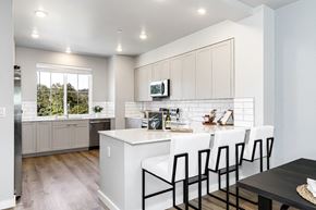 Duvall townhouse for rent - a kitchen with white cabinets and a white island with three white chairs