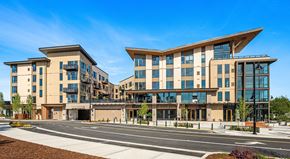 Woodinville apartment for rent - A modern building with a curved glass facade is situated on a street corner.
