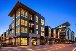 Kenmore apartment for rent - A modern multi-story building with a dark facade and lit windows.