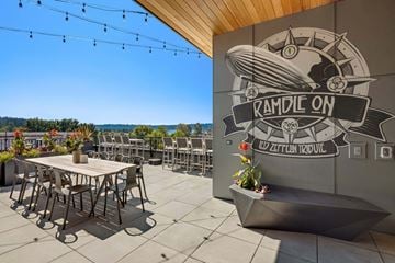 Kenmore apartment for rent - A patio area with tables and chairs and a mural on the wall.