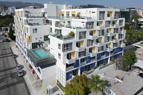Los Angeles apartment for rent - an aerial view of a white building with blue and yellow windows and a pool in front of