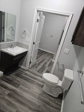Wichita apartment for rent - A white toilet sits in a bathroom next to a sink and a mirror.