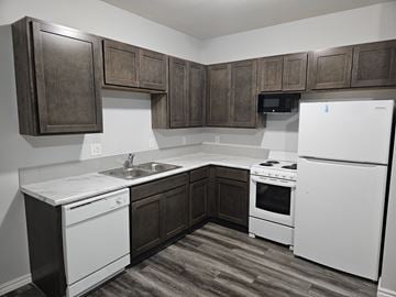 Wichita apartment for rent - A kitchen with white appliances and brown cabinets.