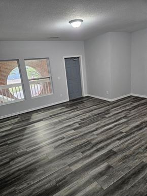 Wichita apartment for rent - A room with a grey door and a window with a view of a red brick building.
