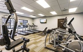 Wichita apartment for rent - a gym with various exercise equipment and a tv on the wall