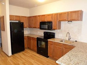 Wichita apartment for rent - a kitchen with black appliances and wooden cabinets