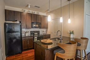 Wichita apartment for rent - a kitchen with black appliances and a island with chairs