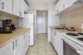 Ottawa apartment for rent - A kitchen with white cabinets and a stove top oven.