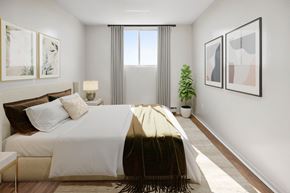 Ottawa apartment for rent - A bedroom with a large bed and a potted plant.
