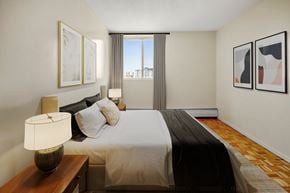 Ottawa apartment for rent - A bedroom with a large bed and a window overlooking the city.