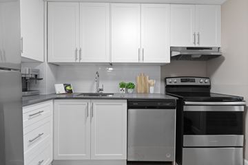 Ottawa apartment for rent - A modern kitchen with white cabinets and stainless steel appliances.