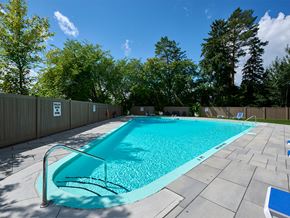 Ottawa apartment for rent - A rectangular pool with a metal railing and a blue bench.