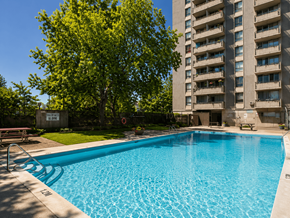 Ottawa apartment for rent - A blue swimming pool in front of a tall building.