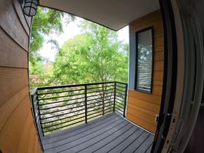 Indianapolis apartment for rent - A balcony with a black railing and a view of trees.