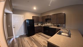 Indianapolis apartment for rent - A kitchen with a black refrigerator and brown cabinets.