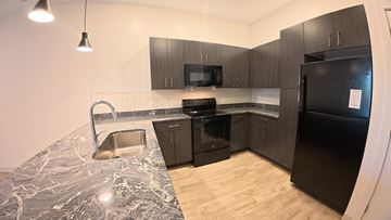 Indianapolis apartment for rent - A kitchen with black appliances and a marble counter top.