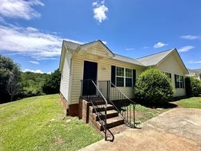 Anderson apartment for rent - A house with a white siding and a black door is surrounded by a green lawn.