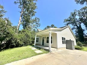 Greenville house for rent - A small white house with a porch and a garage door.