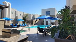 Canoga Park apartment for rent - A pool area with blue umbrellas and chairs.