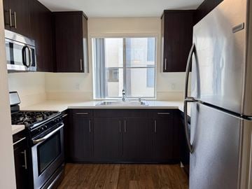 Canoga Park apartment for rent - A kitchen with dark brown cabinets and a stainless steel refrigerator.