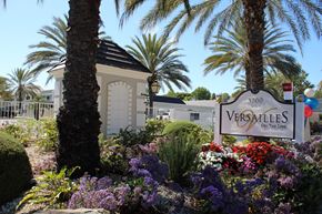 Santa Ana apartment for rent - A Versailles sign is in front of a building and some trees.