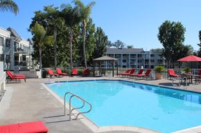 Santa Ana apartment for rent - A swimming pool surrounded by red chairs and trees.
