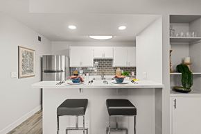 Tucson apartment for rent - a kitchen with white cabinets and a white counter top with two stools in front of it