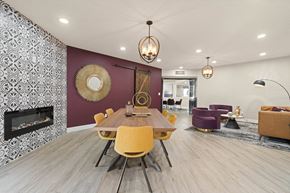 Tucson apartment for rent - a dining area with a wooden table and yellow chairs and a purple accent wall with a fireplace