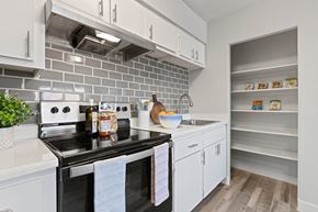 Tucson apartment for rent - a kitchen with white cabinets and a black stove top oven