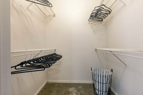 Dallas apartment for rent - A white closet with black hangers and a striped laundry basket.