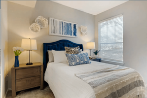 Dallas apartment for rent - A bedroom with a white bed and a blue headboard.
