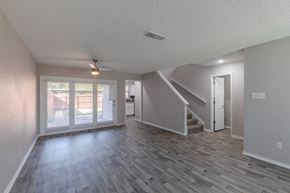 Euless townhouse for rent - A spacious room with a staircase and sliding glass doors.