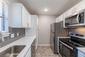 Euless townhouse for rent - A kitchen with stainless steel appliances and white cabinets.