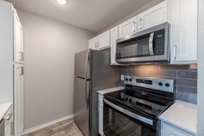 Euless townhouse for rent - A kitchen with a stainless steel refrigerator, microwave, and oven.