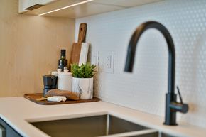 Winnipeg apartment for rent - a kitchen sink with a black faucet and a wooden tray with kitchen implements
