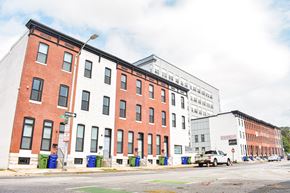 Baltimore apartment for rent - A row of red brick buildings with a white car parked in front of the white building.