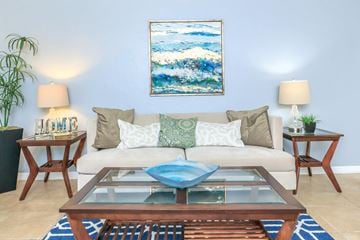 Gainesville apartment for rent - A living room with a white couch, a blue coffee table, and a painting on the wall.