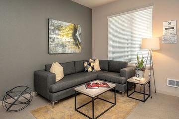 Oakland apartment for rent - A living room with a grey couch, a coffee table, and a painting on the wall.