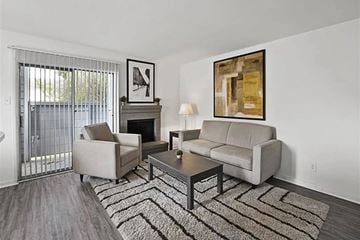 Houston apartment for rent - A living room with a grey couch, a coffee table, a fireplace, and a painting on the wall.