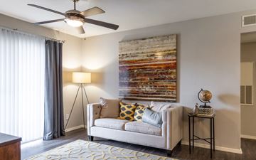 Houston apartment for rent - A living room with a couch, a ceiling fan, and a painting on the wall.