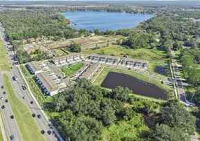 St. Cloud townhouse for rent - A large building complex is surrounded by a lake and greenery.