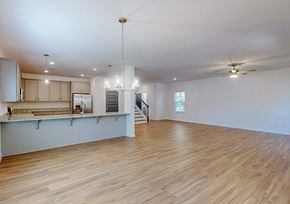 Covington apartment for rent - A spacious room with wooden floors and a kitchen area with white cabinets.