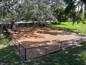 Eustis townhouse for rent - A fenced in area with a dirt ground and trees in the background.